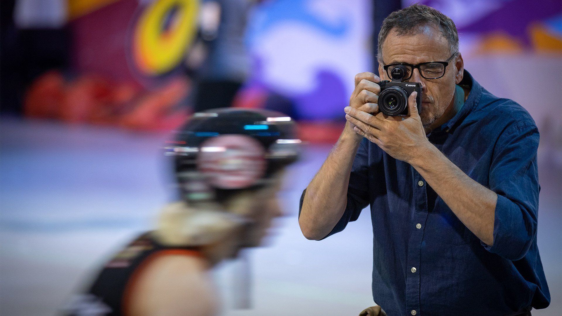 Photographer Piotr Malecki is in sharp focus as he photographs a fast-moving roller skater, who is blurred.